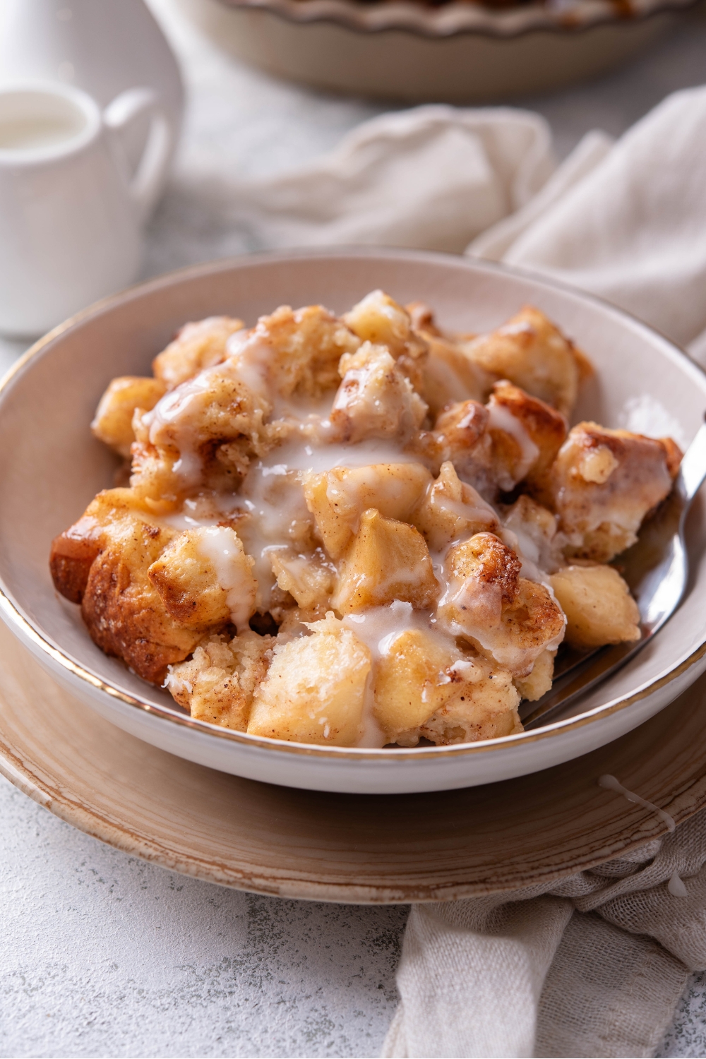 A bowl with Cinnamon Rolls With Apple Pie Filling drizzled with icing.