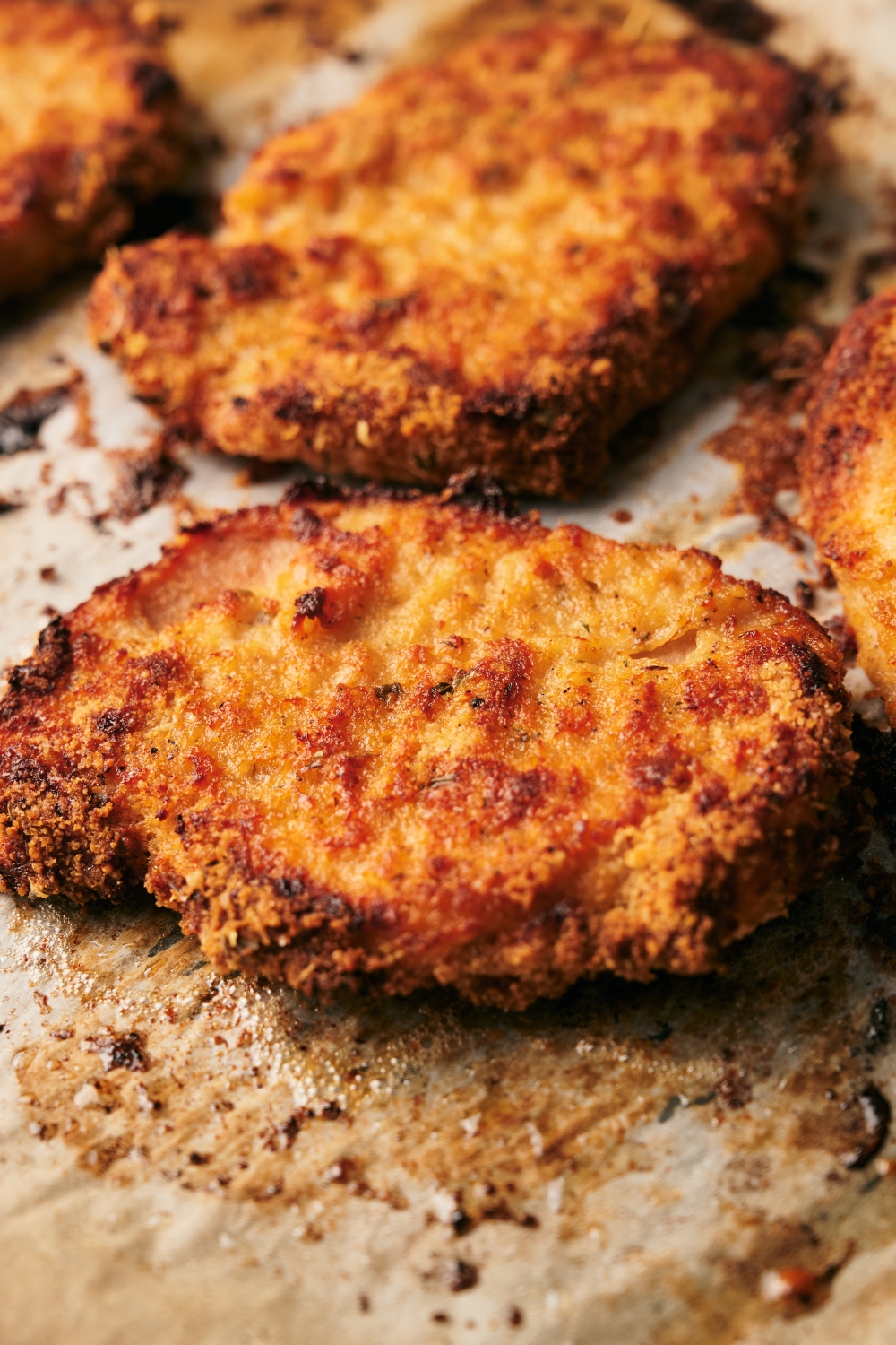 Close up of a crispy breaded pork chop on a piece of parchment paper.