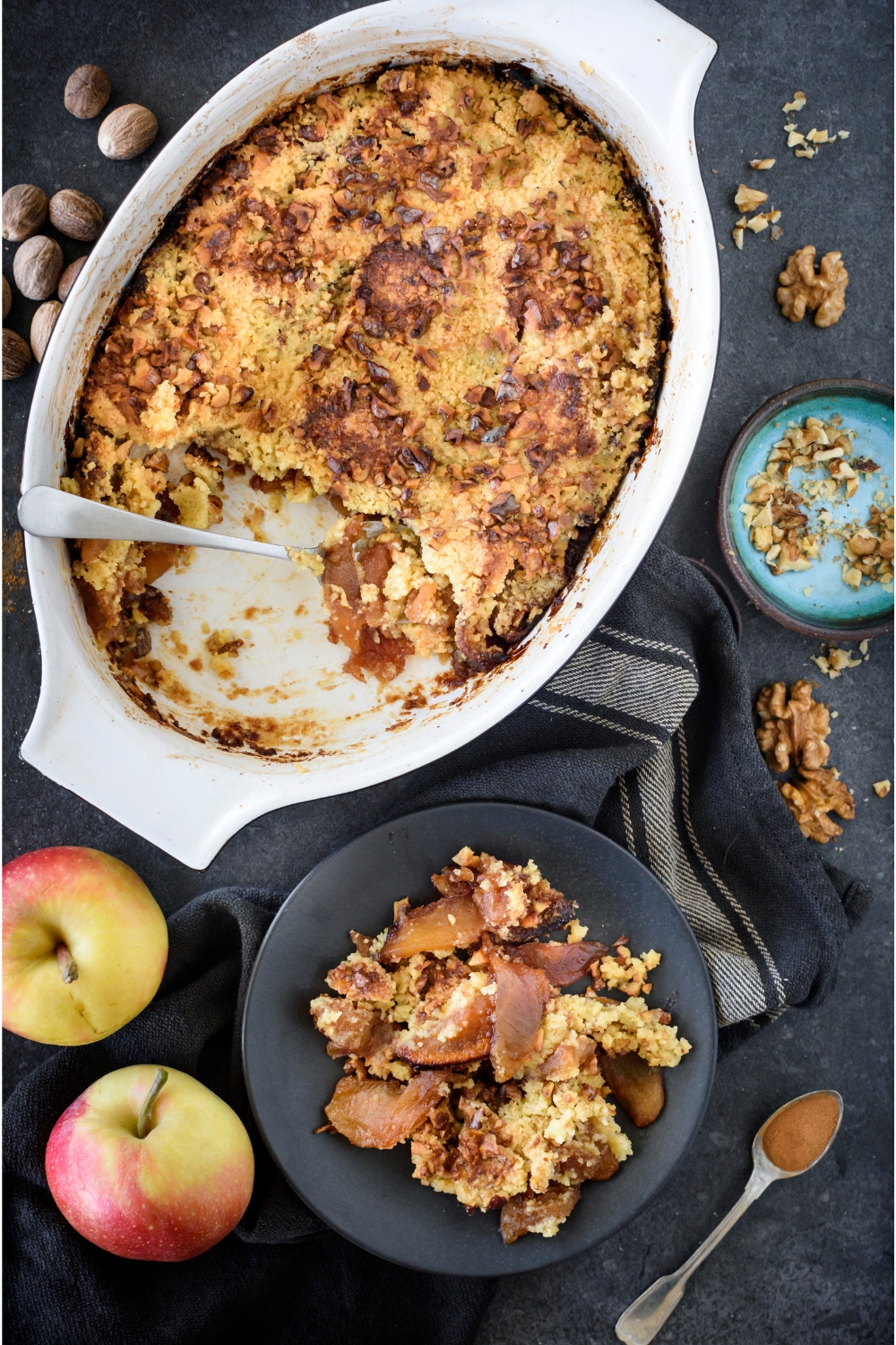 A baking dish filled with apple dump cake and a serving has been scooped out and put on a plate next to the baking dish.