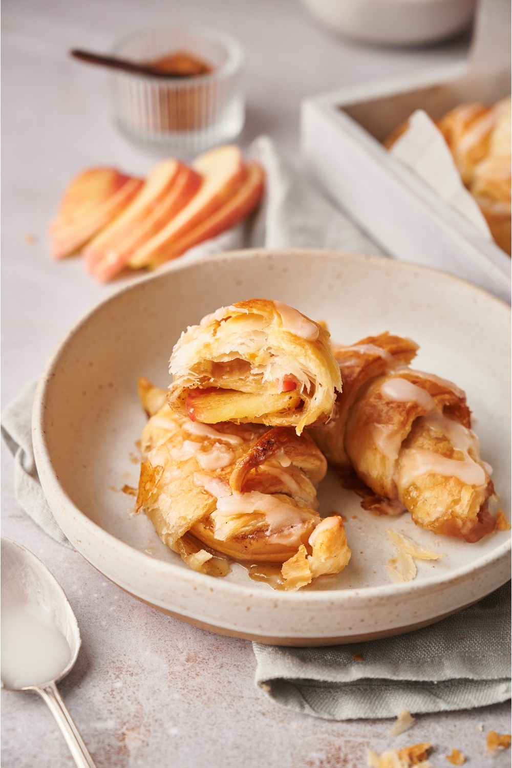 A plate with three apple turnovers and one has been sliced in half to reveal an apple slice in the center.