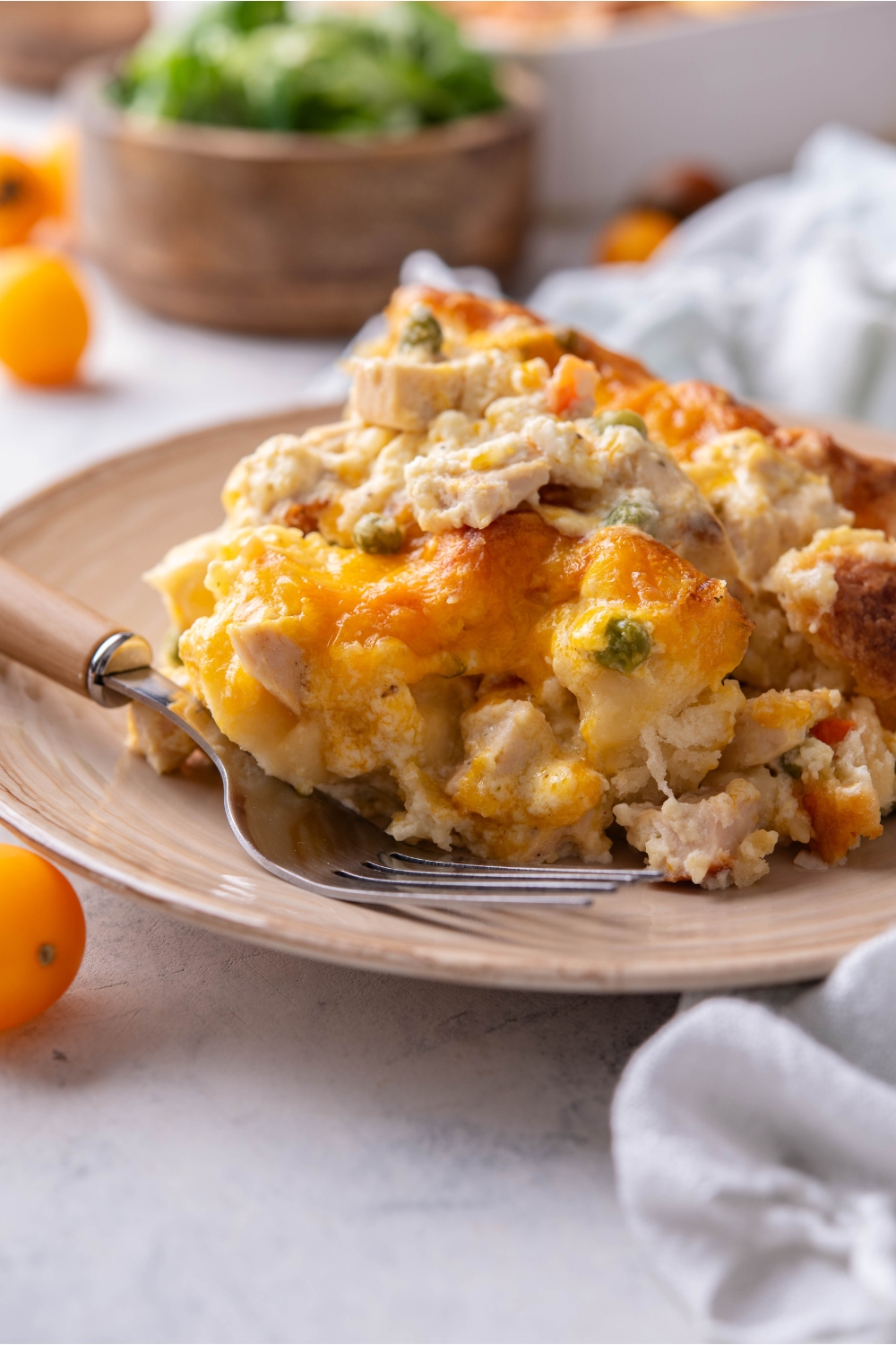A serving of chicken and biscuit casserole piled high with a fork on the plate.