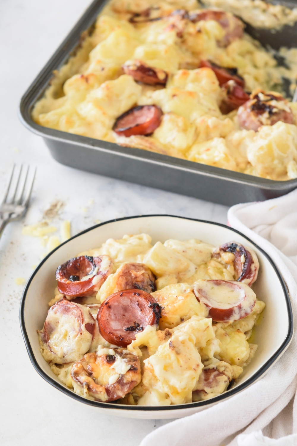 A bowl of kielbasa sausage casserole next to a baking dish filled with more casserole.