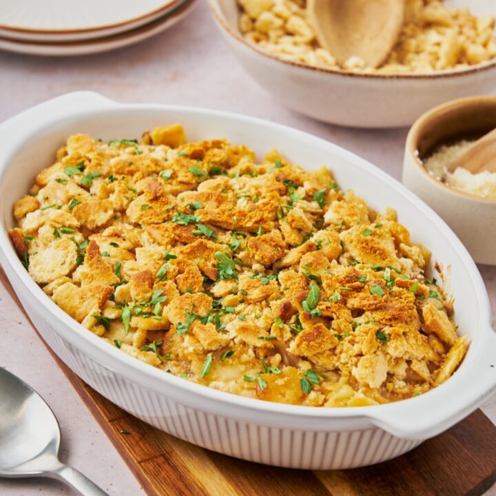 A baking dish filled with onion casserole covered in cracker crumbs and green herbs.