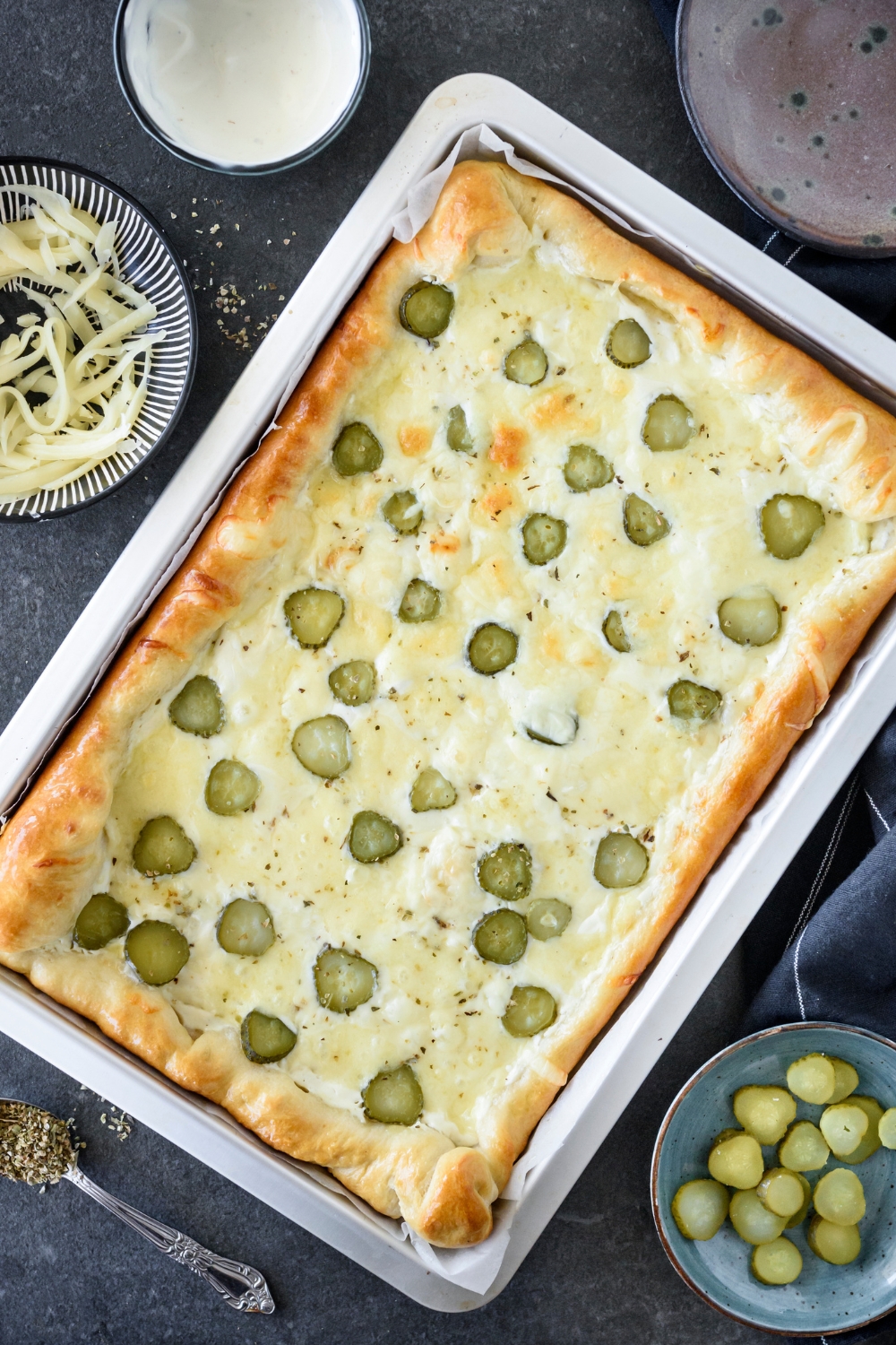 Freshly baked pickle pizza on a baking sheet lined with parchment paper.
