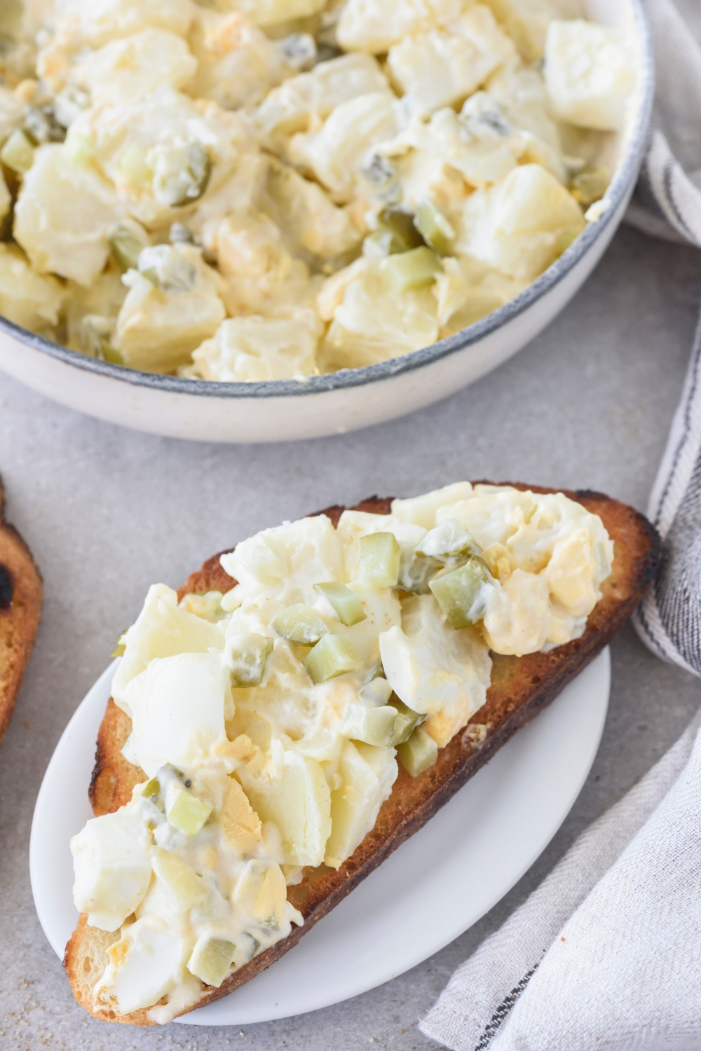 A bowl with Hellmann's Potato Salad and a plate with potato salad on a piece of toasted bread.
