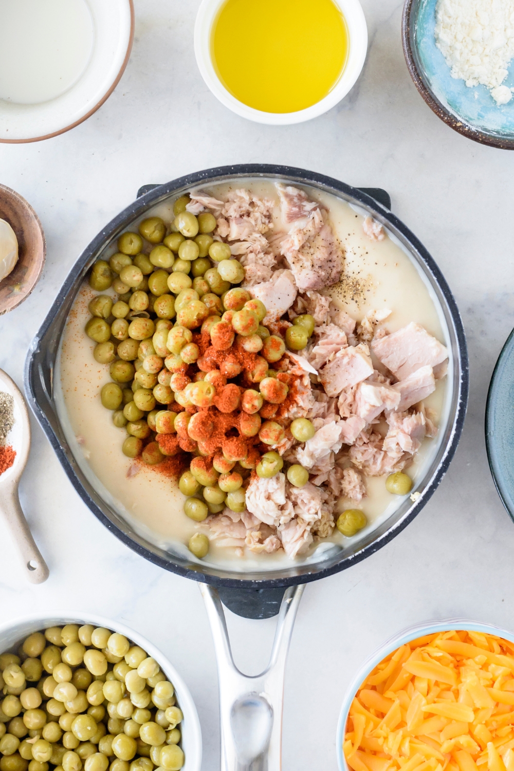 A pot filled with canned tuna, cooked peas, and spices in a cream sauce.