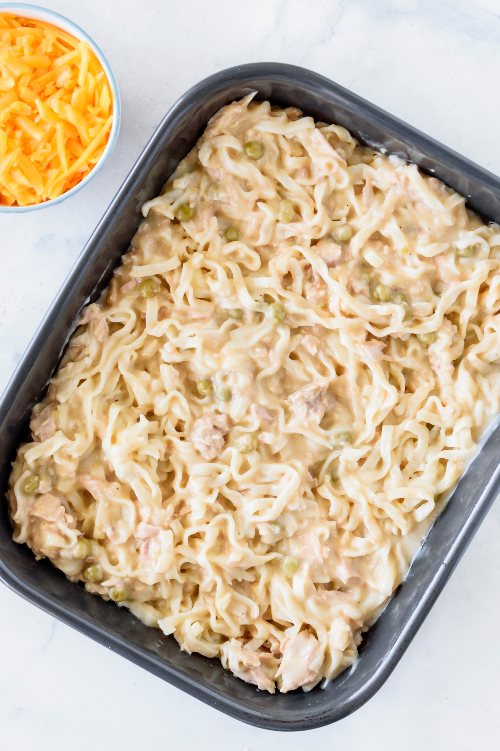 A baking dish filled with egg noodles and tuna in a creamy sauce.