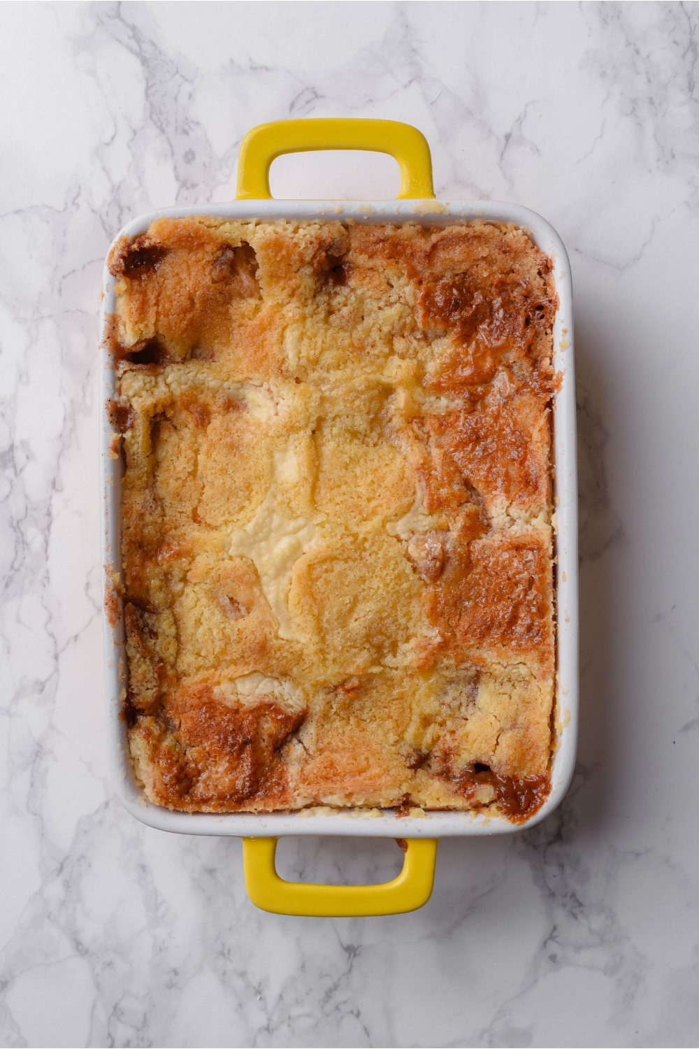 A baking dish filled with freshly baked dump cake covered in a golden brown cake topping.