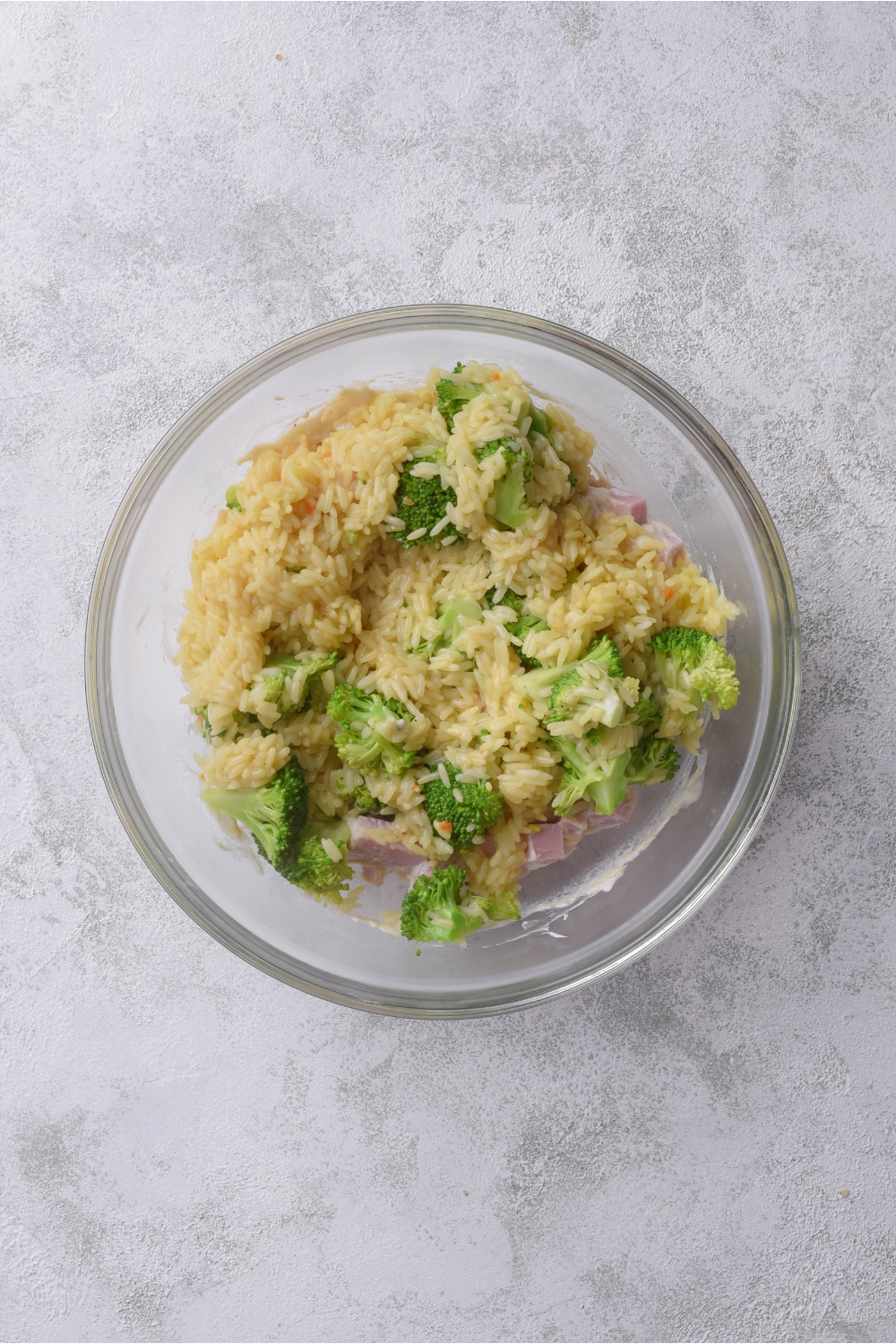 A bowl filled with cooked rice, cooked broccoli, and ham.