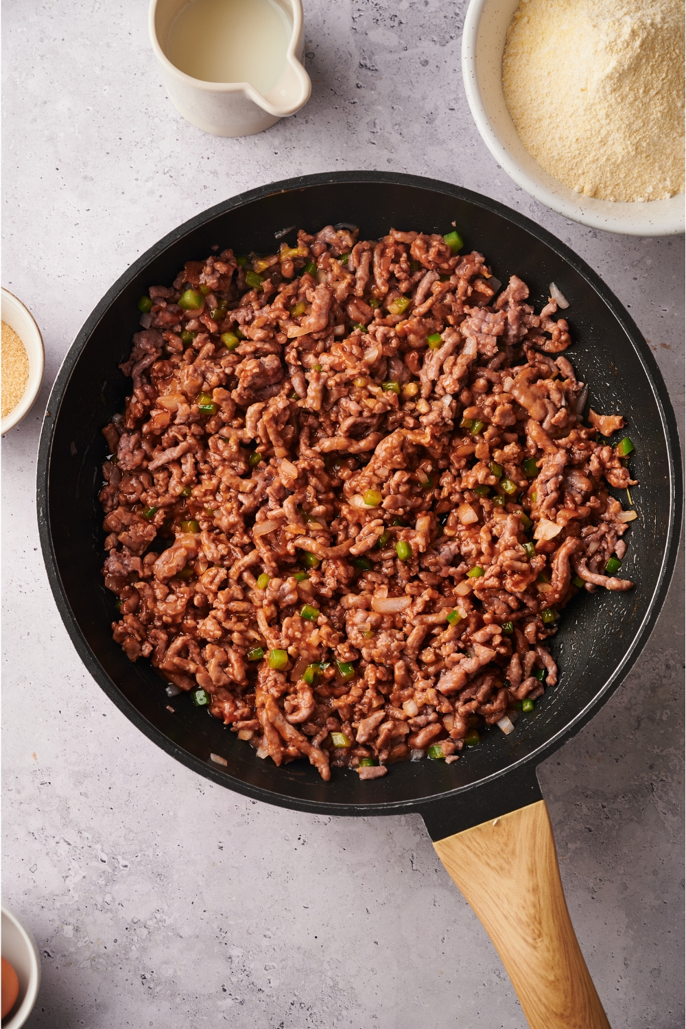 A skillet filled with cooked and seasoned ground beef mixed with peppers and onions.