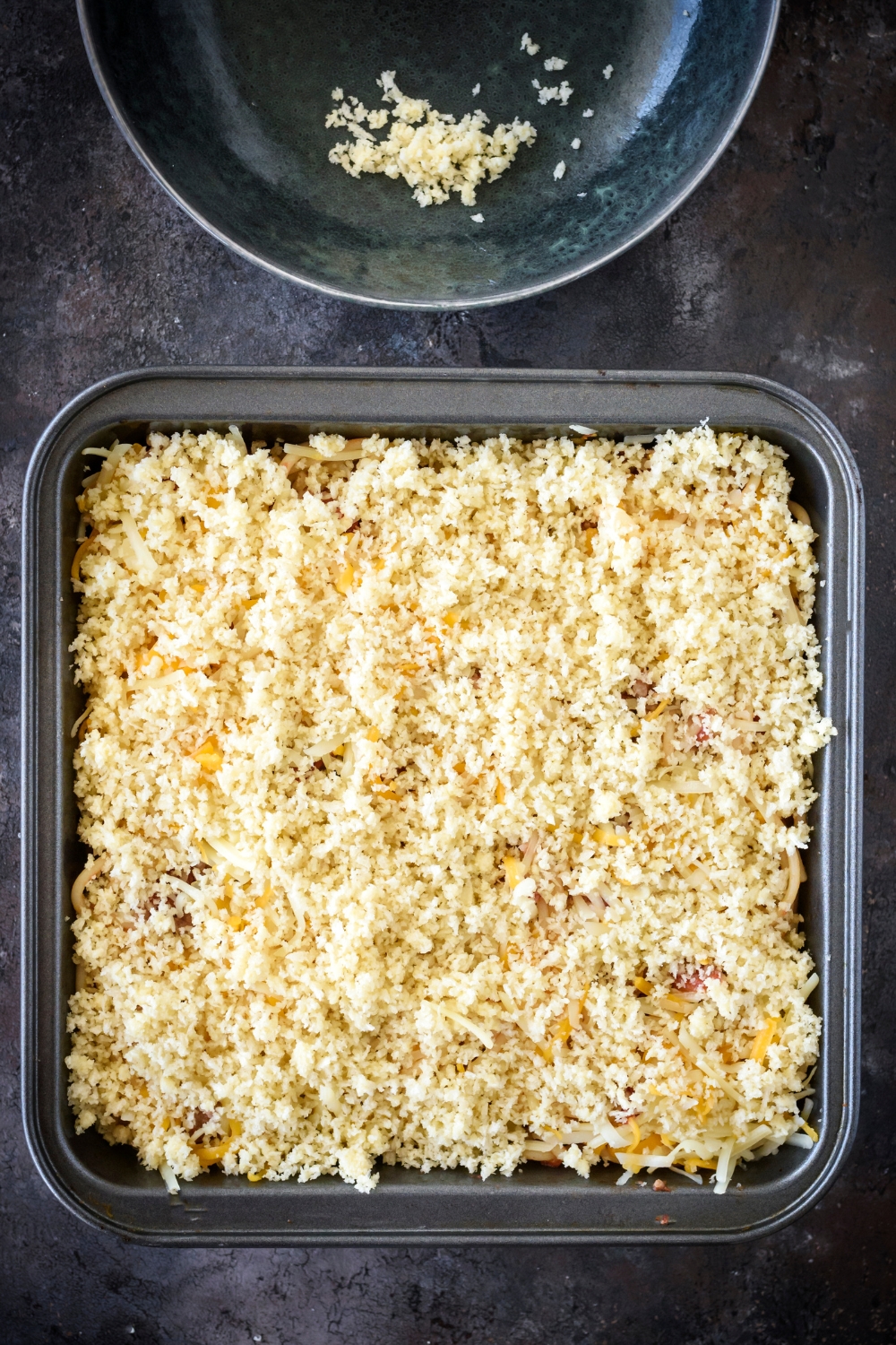 A square baking dish filled with casserole covered in bread crumbs.