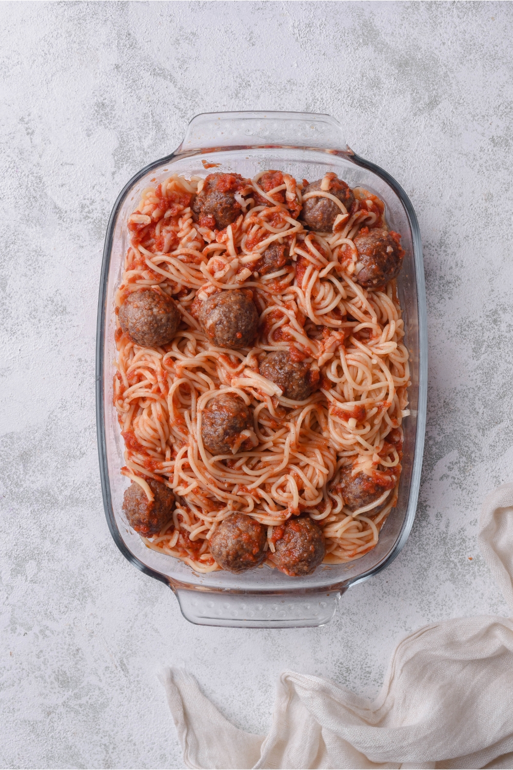 A baking dish filled with spaghetti and meatballs in marinara sauce.