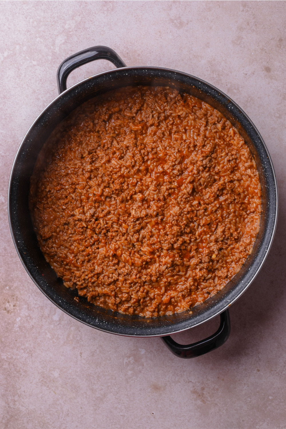 A skillet filled with cooked ground beef in a tomato sauce.