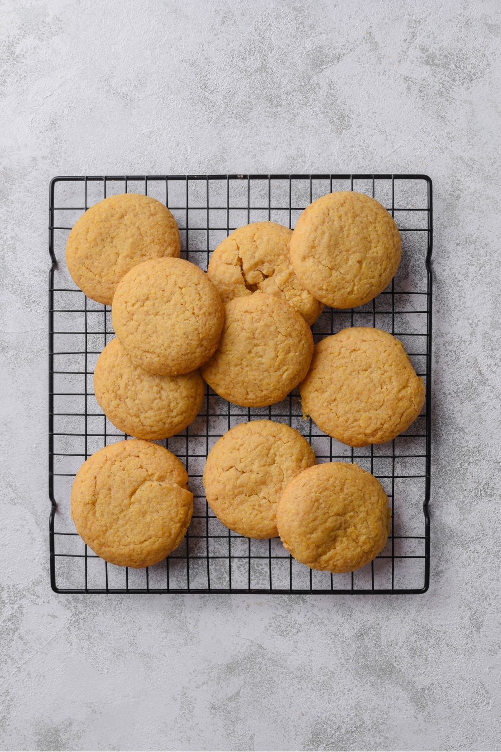 A pile of freshly baked cornbread cookies on a wire rack.