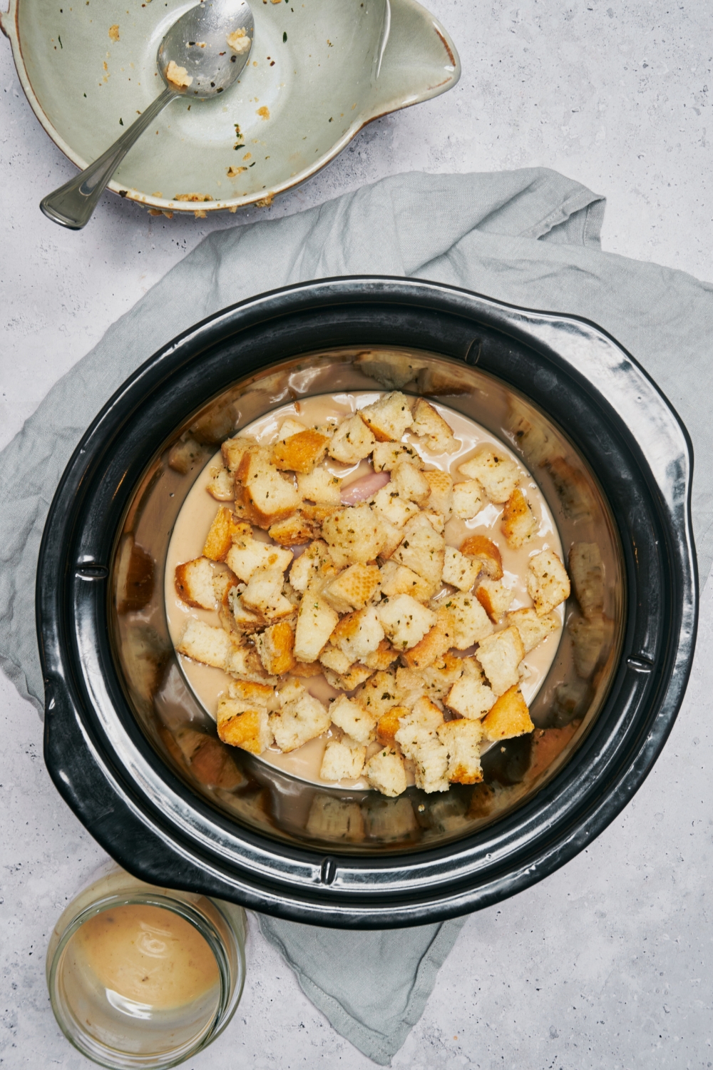 A slow cooker filled with raw pork chops covered in a creamy soup mixture and topped with stuffing.