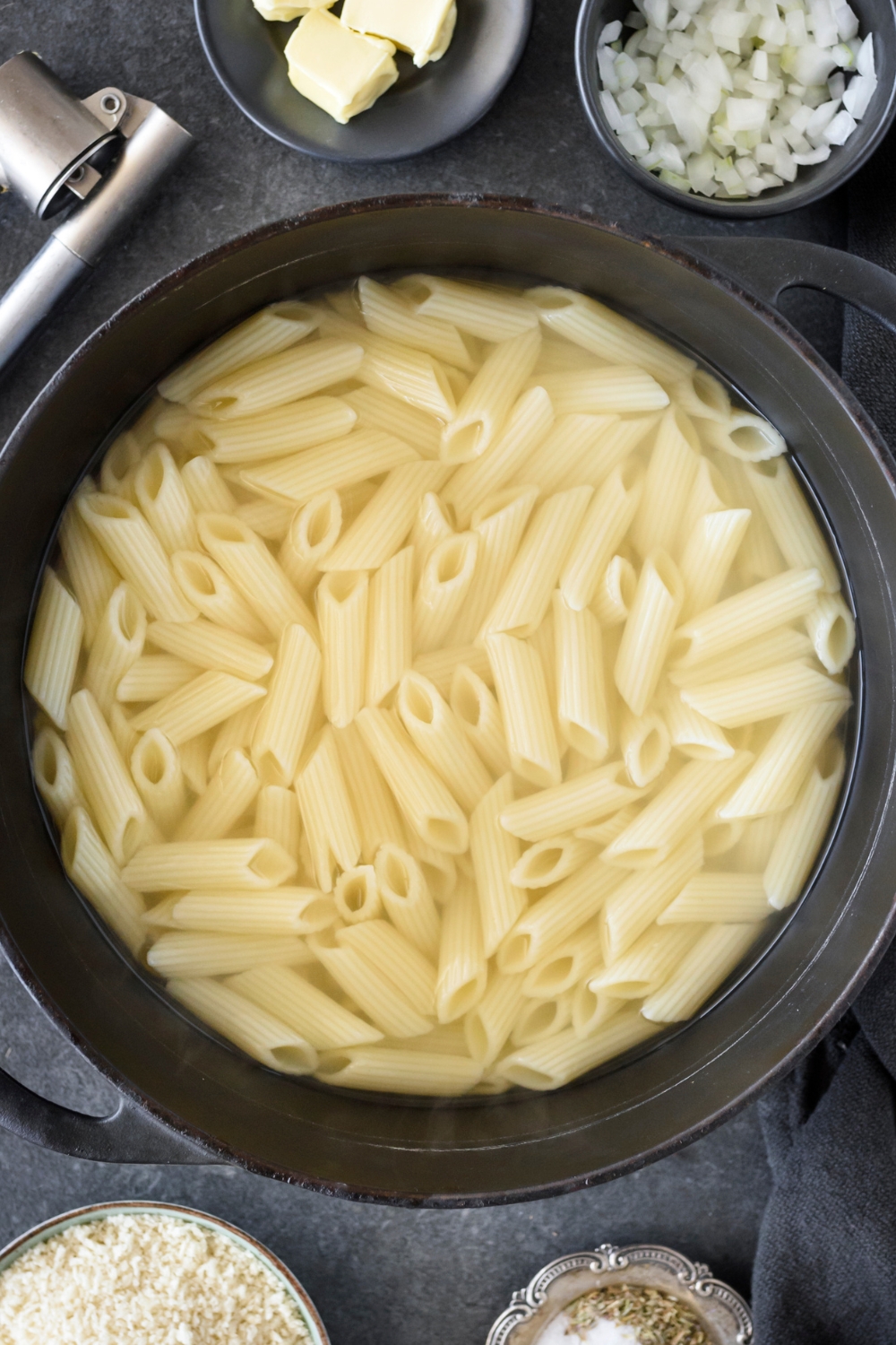 A large pot filled with cooked penne pasta in water.