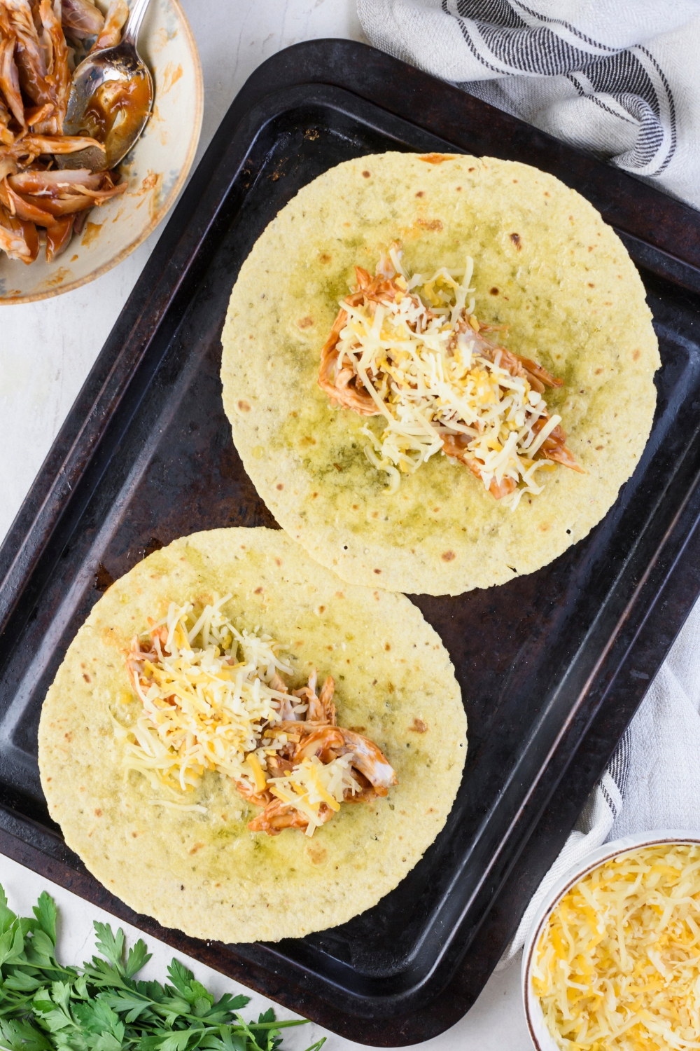 Two corn tortillas filled with shredded chicken in barbecue sauce and topped with shredded cheese.