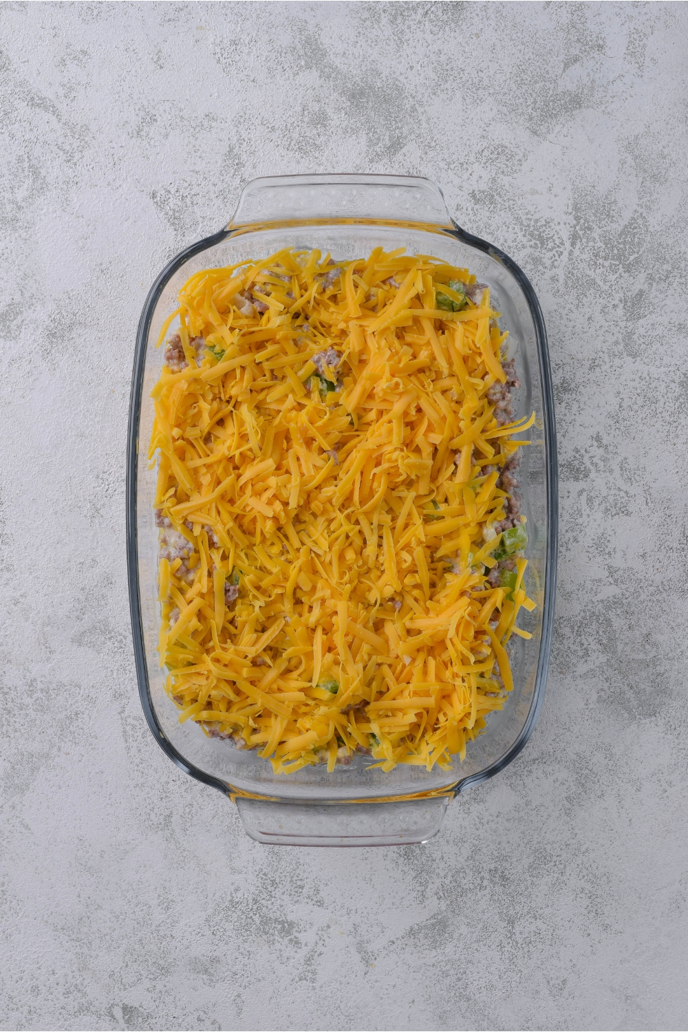 A baking dish filled with casserole covered in a layer of shredded cheese.