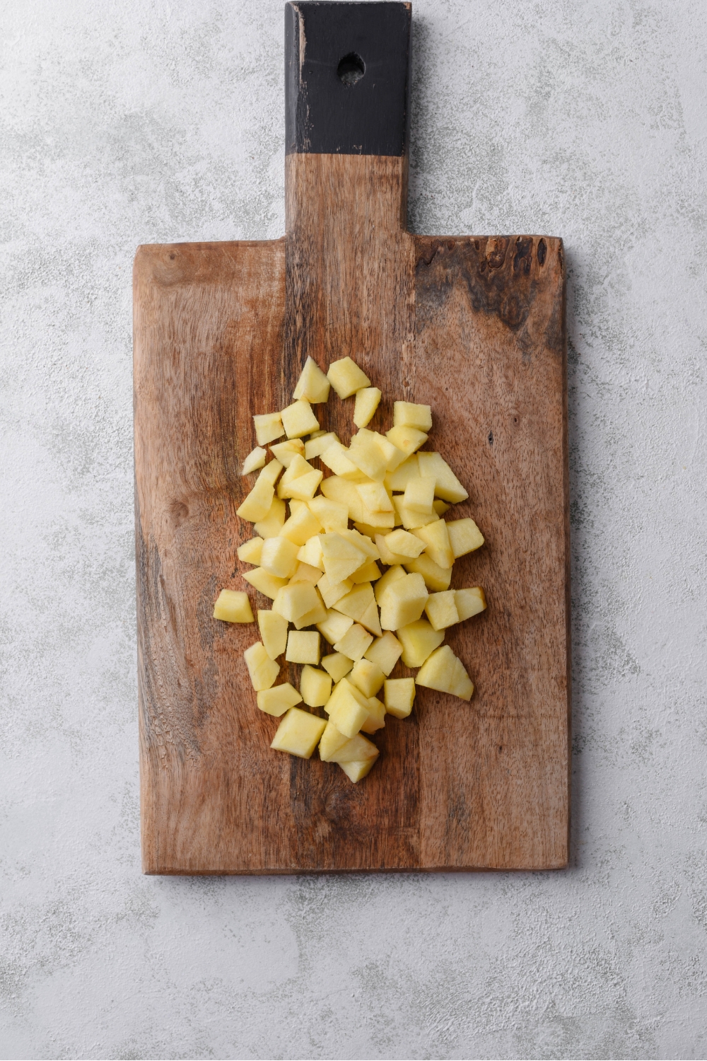A cutting board filled with peeled and diced apples.