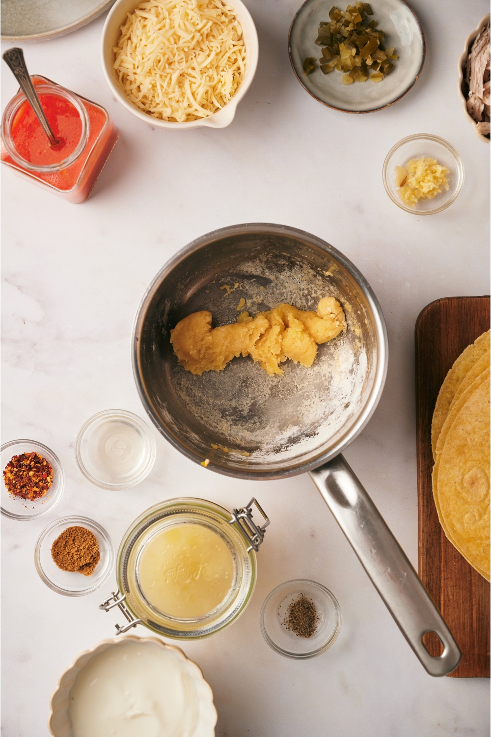 A pot filled with a flour and butter mixture. The pot is surrounded by an assortment of ingredients.