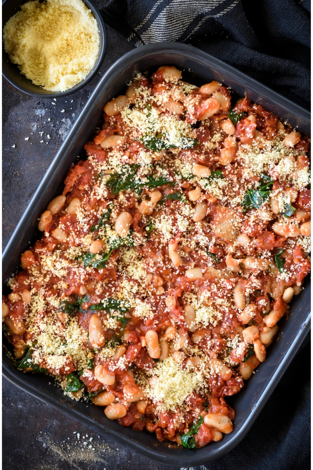 A baking dish filled with tomato casserole covered in parmesan cheese.