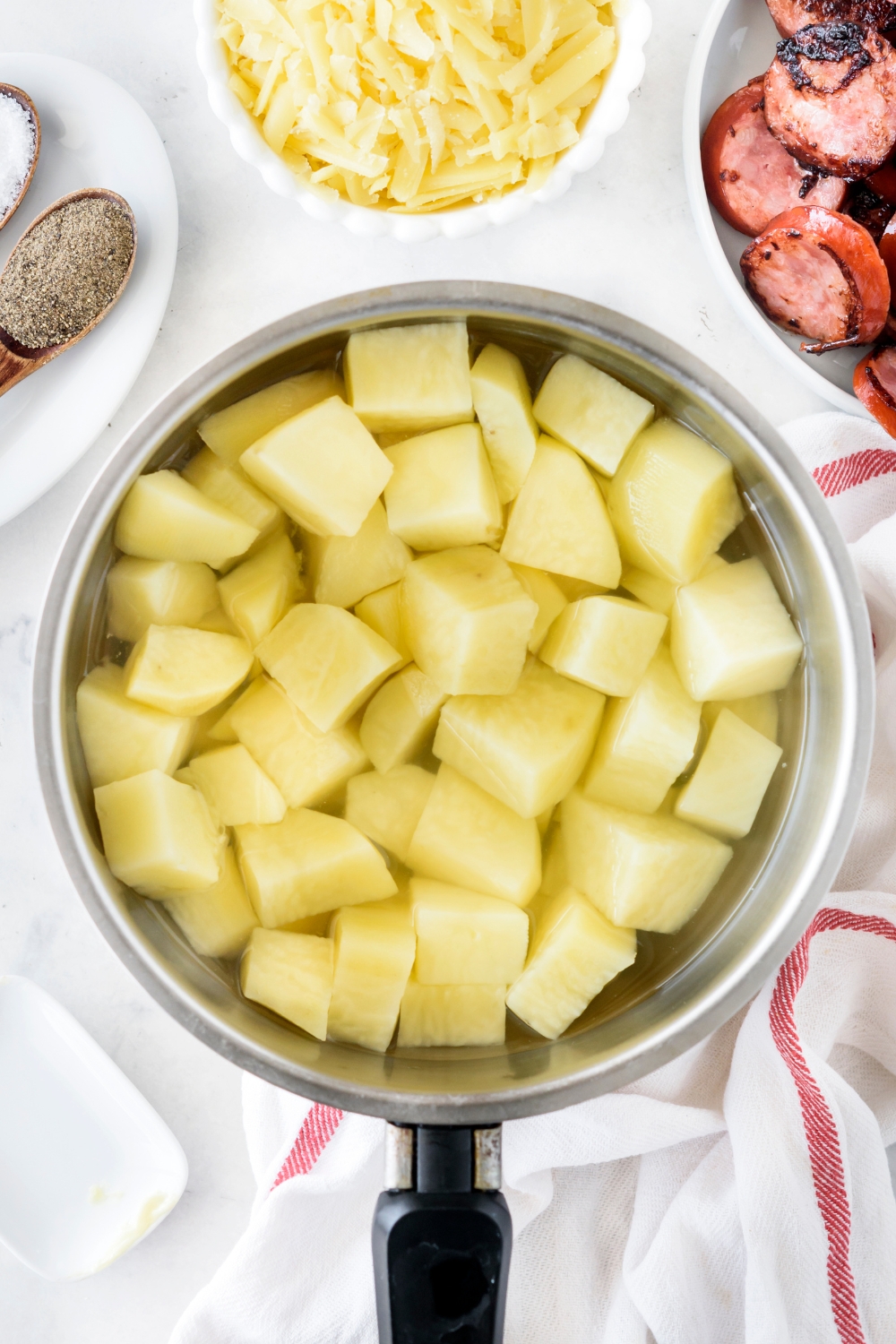A pot filled with peeled and cubed potatoes in water.