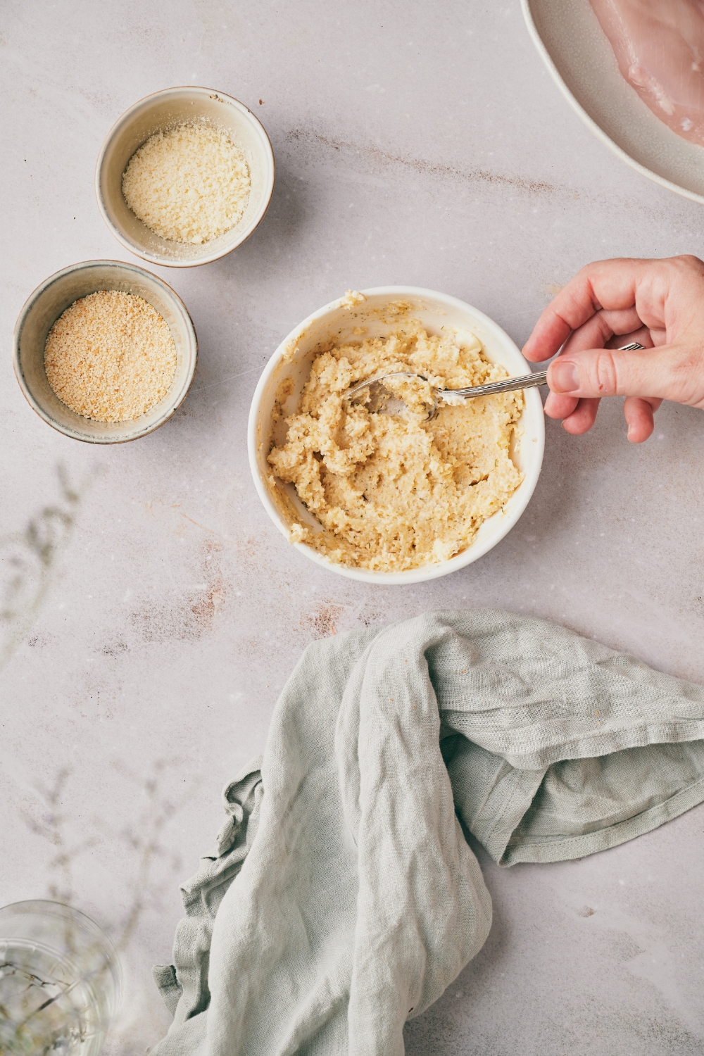 A bowl of mayonnaise and seasonings being mixed using a spoon.