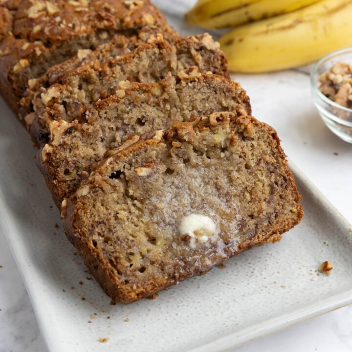 A plate with slices of banana bread with melted butter on top.