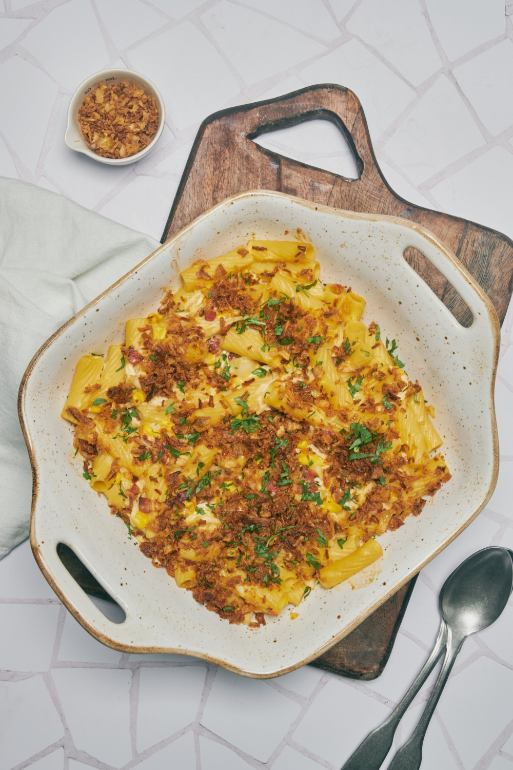 A baking dish filled with freshly baked chicken noodle casserole covered in french fried onions and fresh herbs.