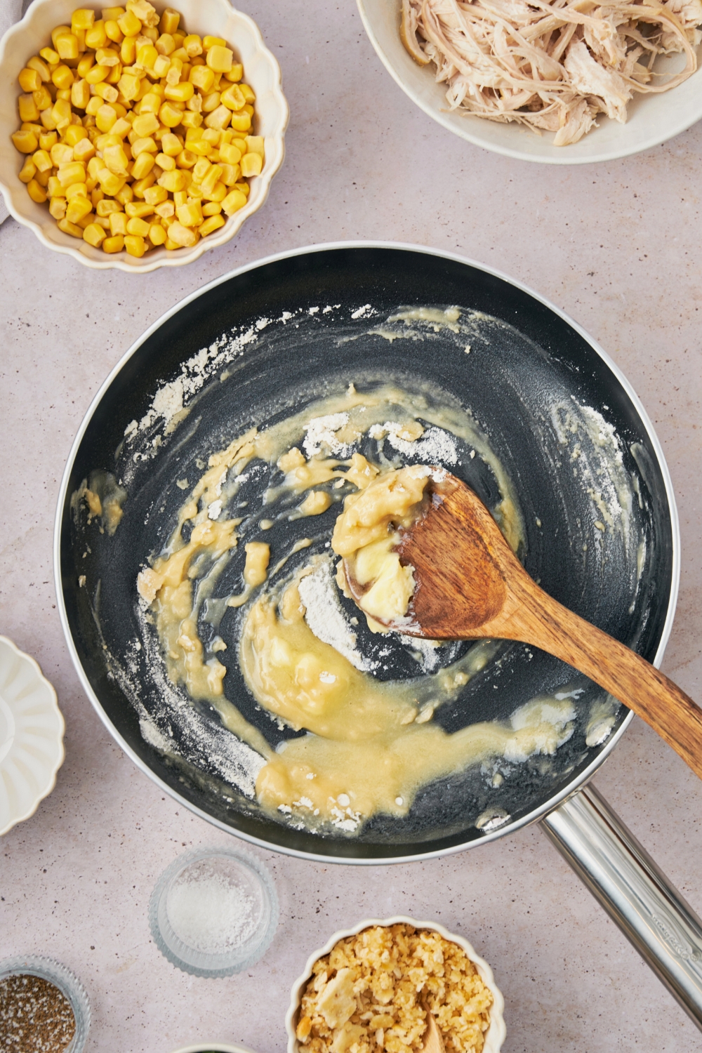 A wooden spoon in a skillet with a butter and flour mix.