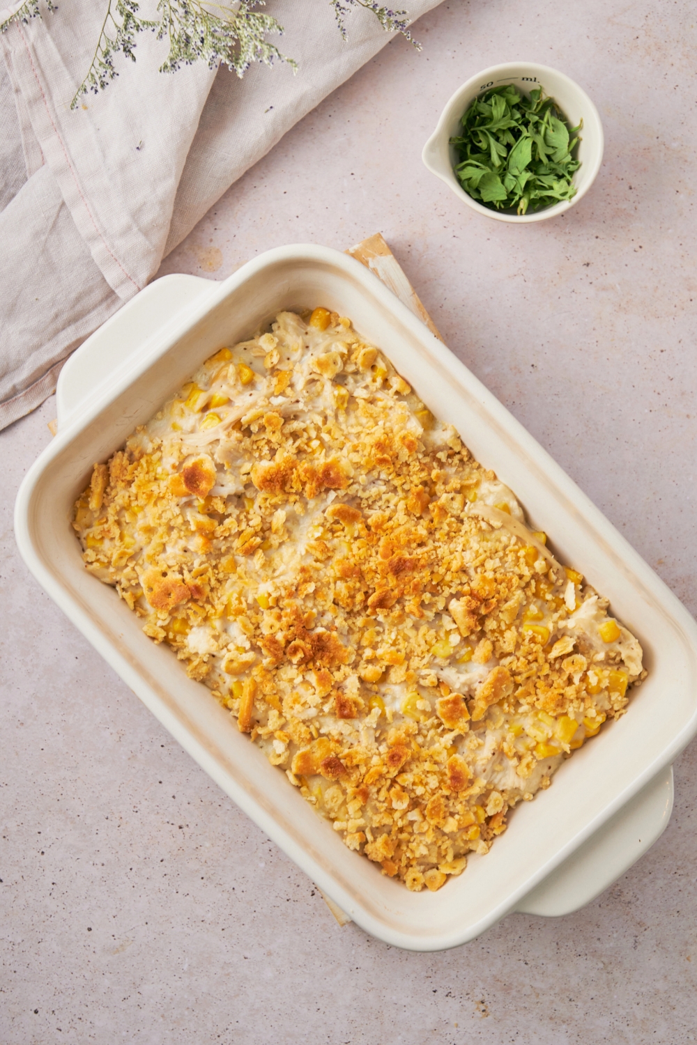 Golden cracker crumbs on top of an amish chicken casserole mix in a white casserole dish on top of a white counter.