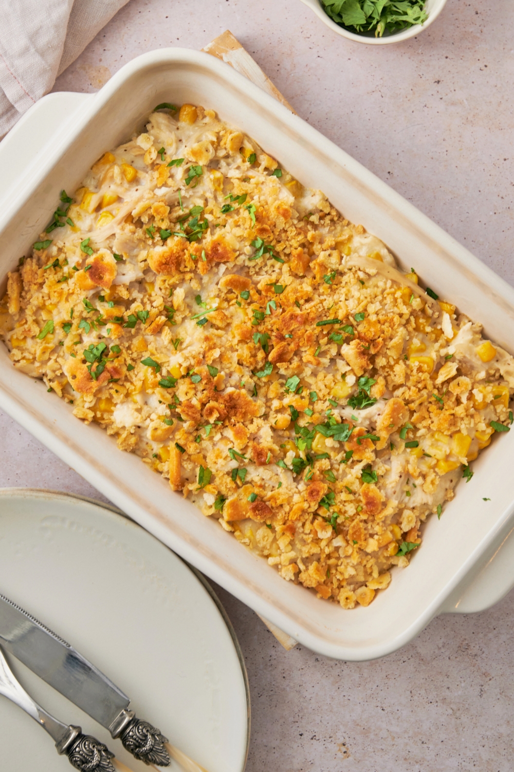 Parsley on top of ritz crackers on an amish chicken casserole mix in a white casserole dish.