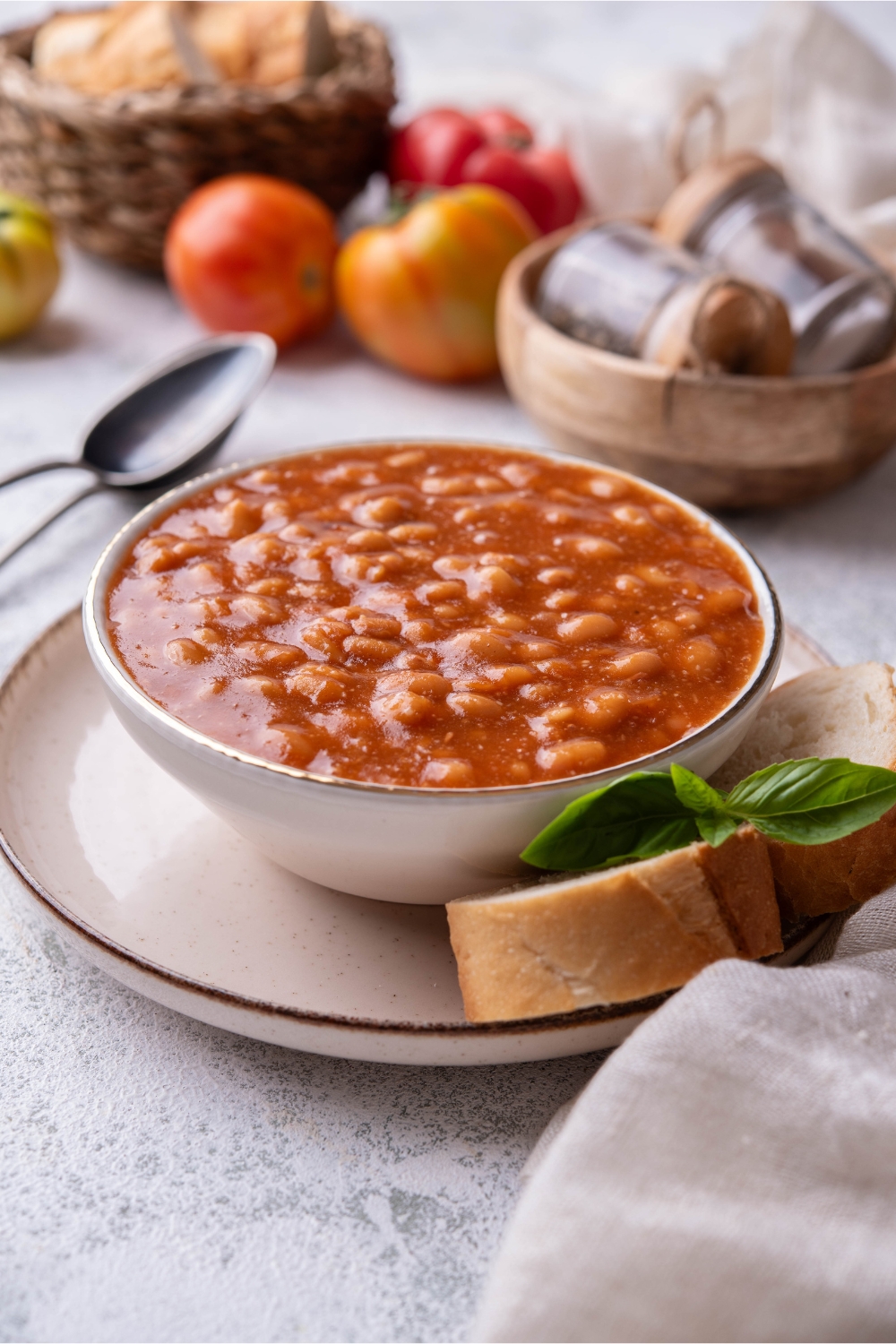 Baked beans in a white bowl served bread slices.