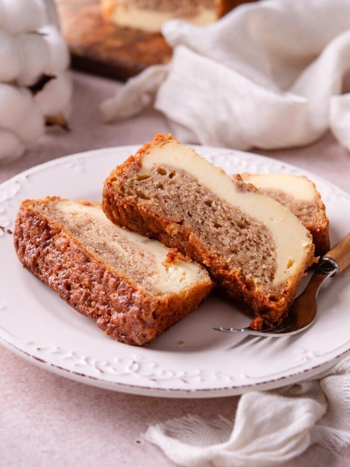 Three slices of cream cheese banana bread overlapping one another on a white plate.