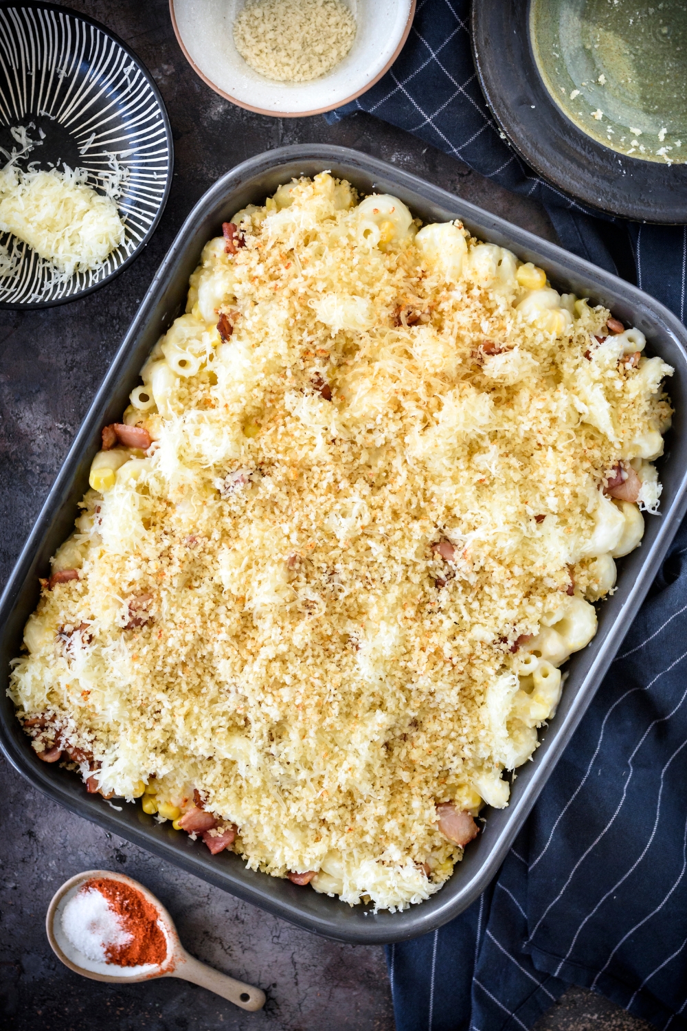 A casserole dish with unbaked macaroni corn casserole topped with panko topping.