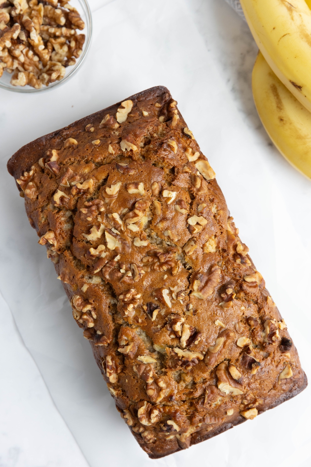 A loaf of banana bread topped with chopped walnuts.