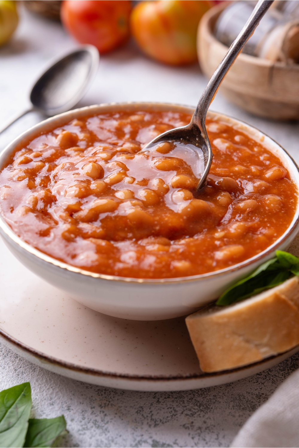 A bowl of baked beans being scooped with a spoon.