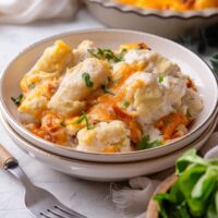 A bowl with cheesy tater tot casserole garnished with green onion.