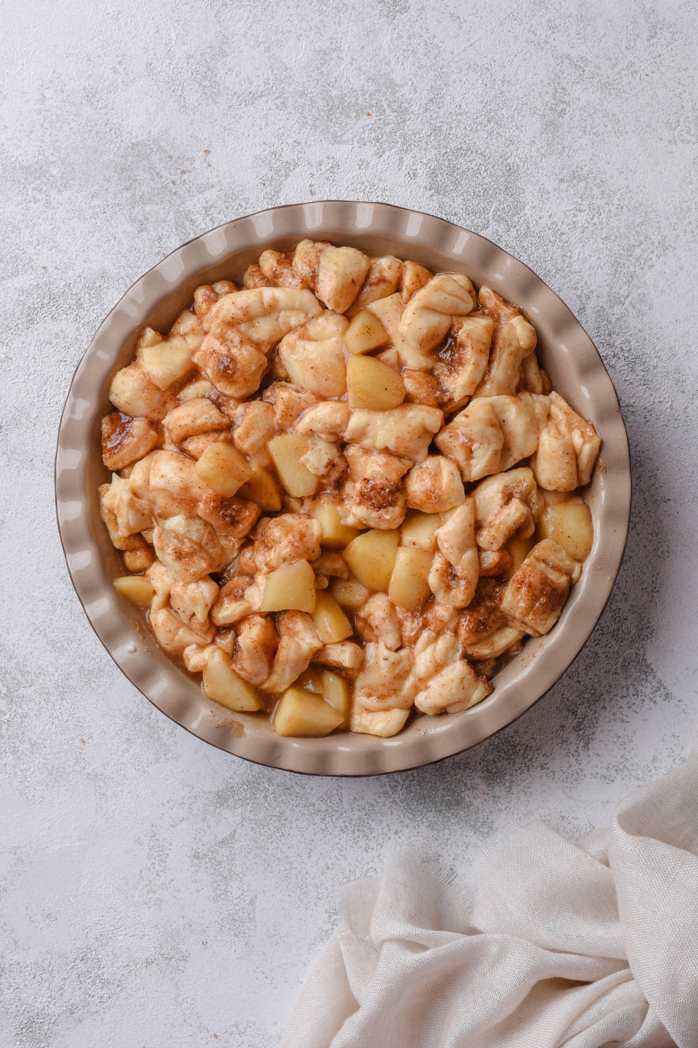 A baking pan with a mixture of cinnamon rolls and apple pie filling.