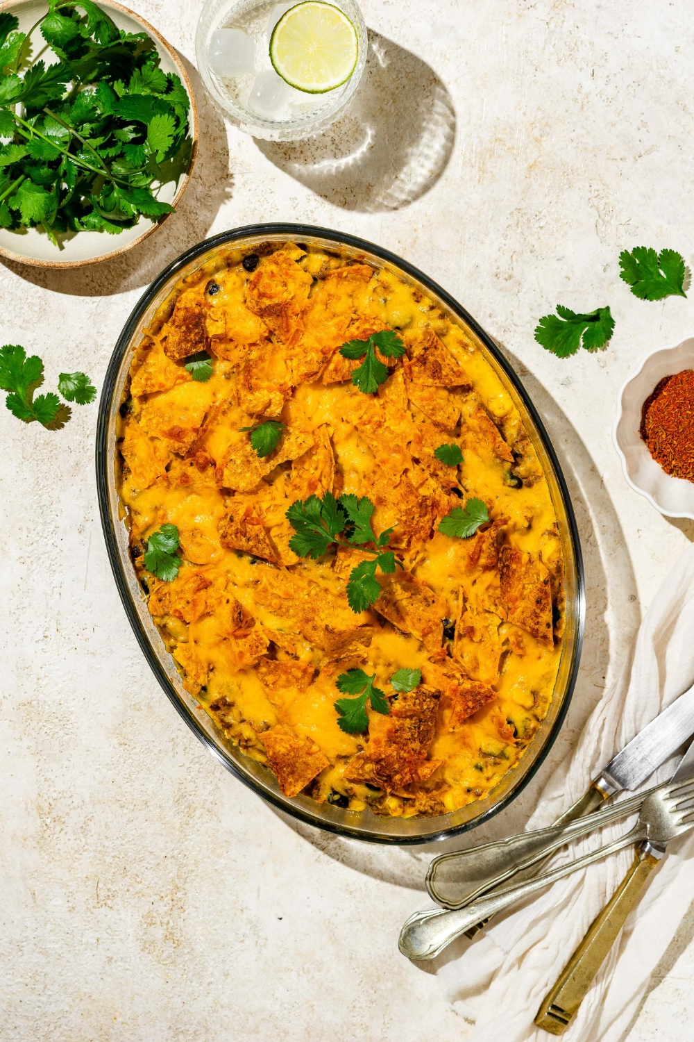 A baked dorito casserole in an oval baking dish on a white counter.