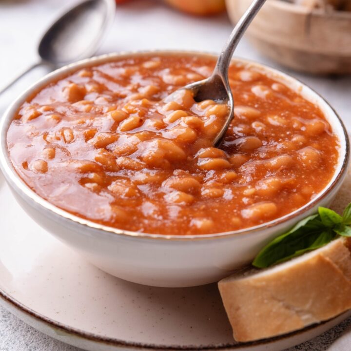 A spoon scooping from a bowl of baked beans.