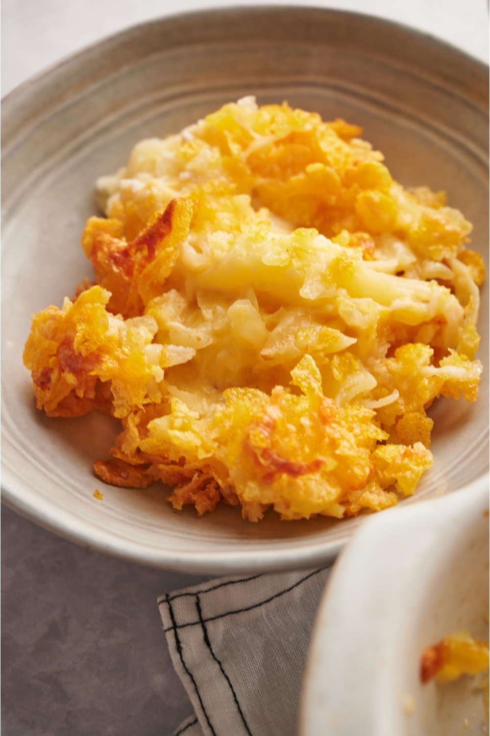 A bowl with a serving of hashbrown casserole in it.