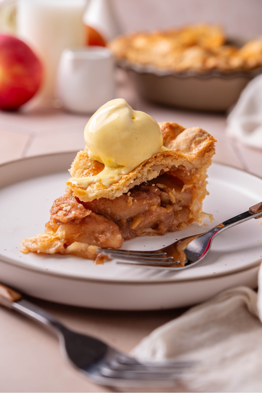 A plate with a slice of apple pie topped with a scoop of vanilla ice cream.