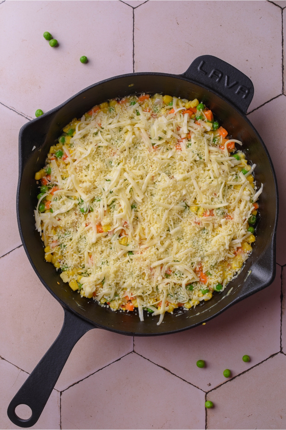 A cast iron skillet with veggies covered with cheese.