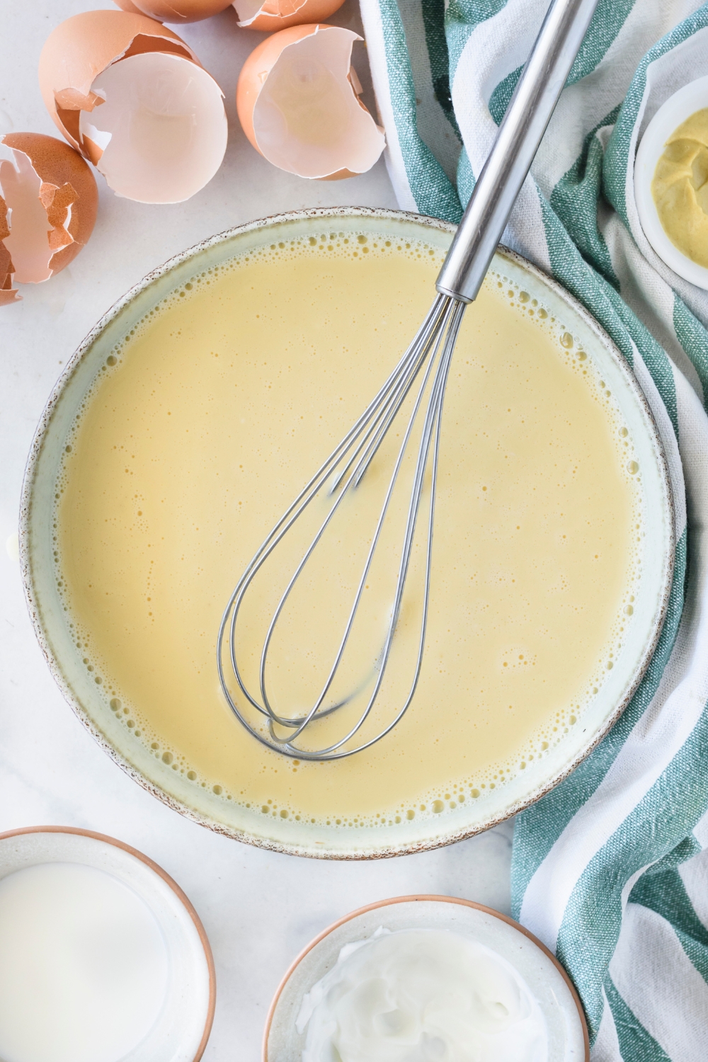 A bowl with a whisk and the egg mixture.