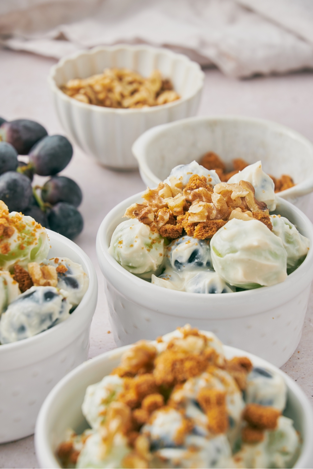 A few small bowls with grape salad topped with chopped nuts and crumbled spiced cookies.