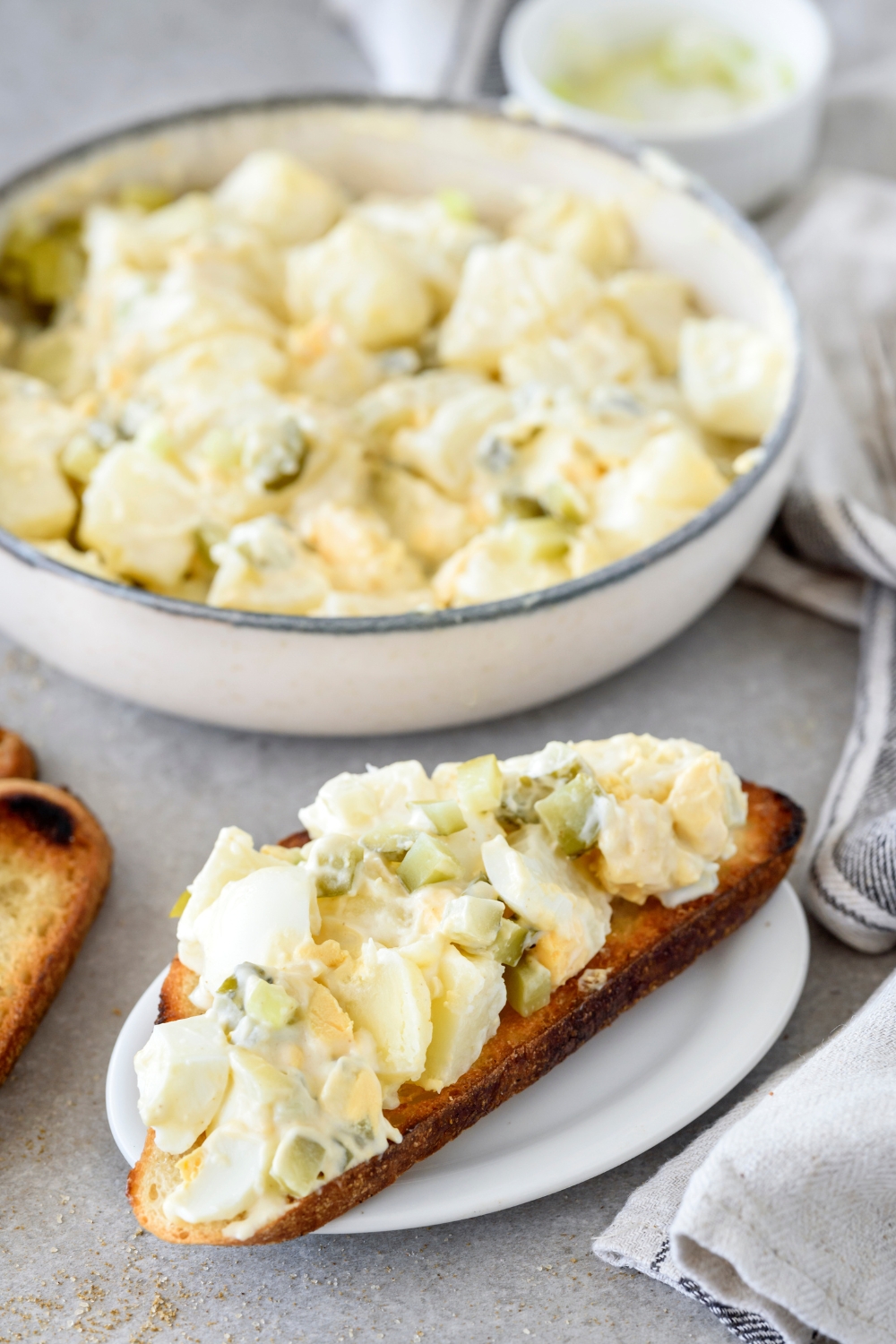 A bowl with Hellmann's Potato Salad and a plate with potato salad on a piece of toasted bread.