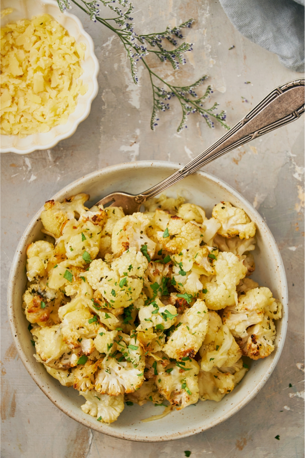 A bowl with cheesy cauliflower and a fork in it.