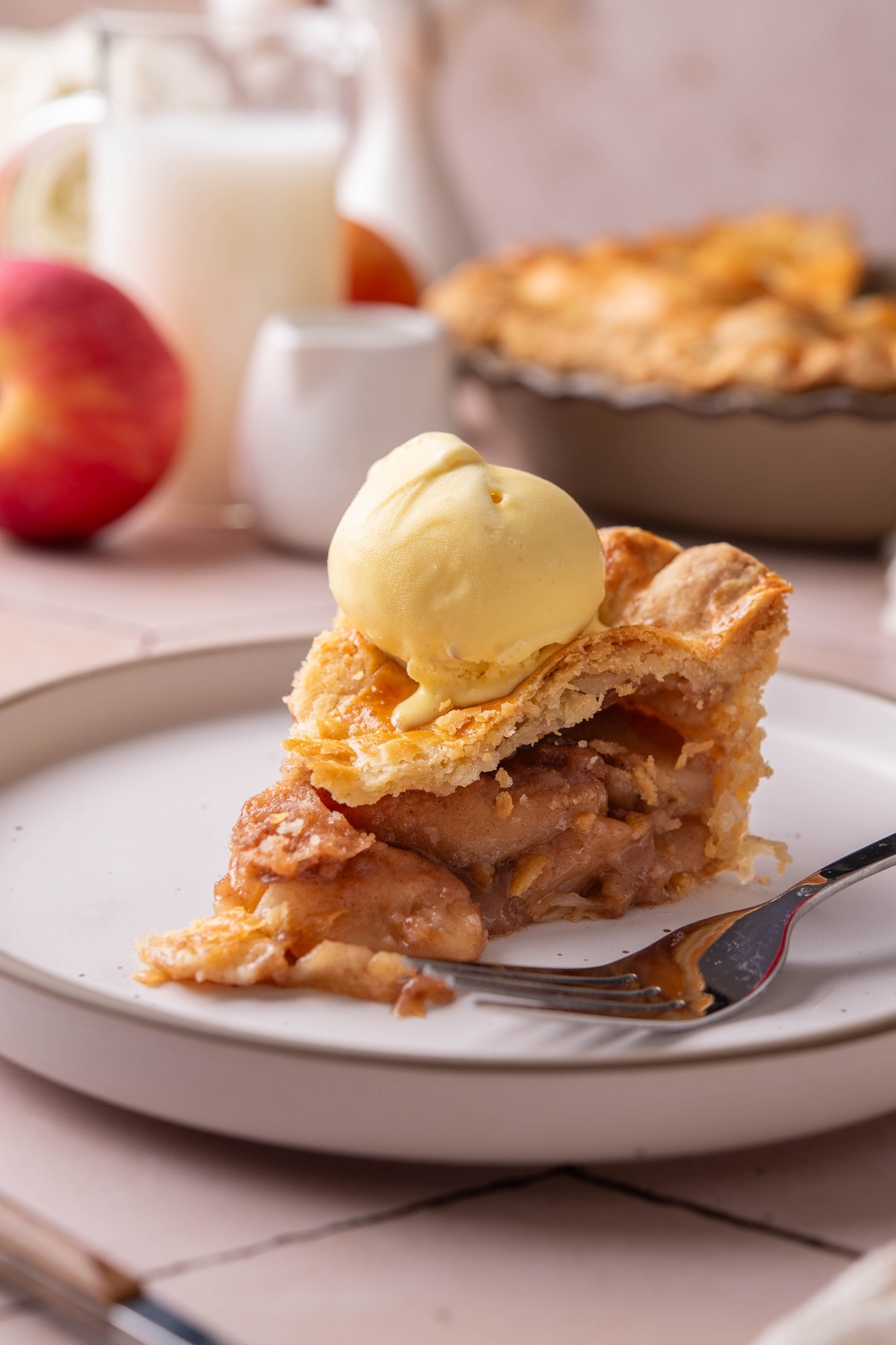 A plate with a slice of apple pie topped with a scoop of vanilla ice cream.