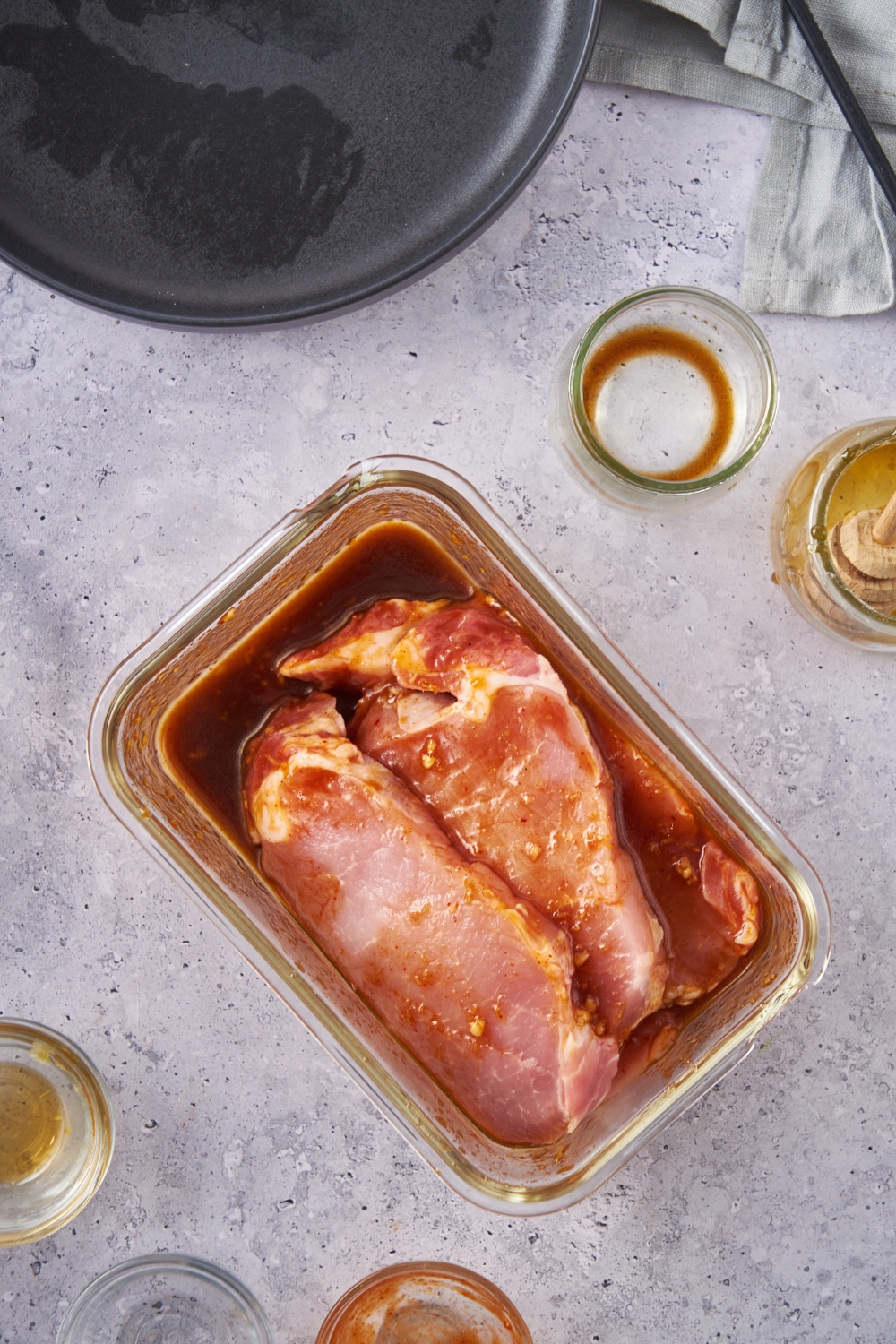 Pork chops marinating in a rectangle glass container.